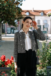 a lady in a white bow tie neck shirt, a grey jacket and a black tulle skirt